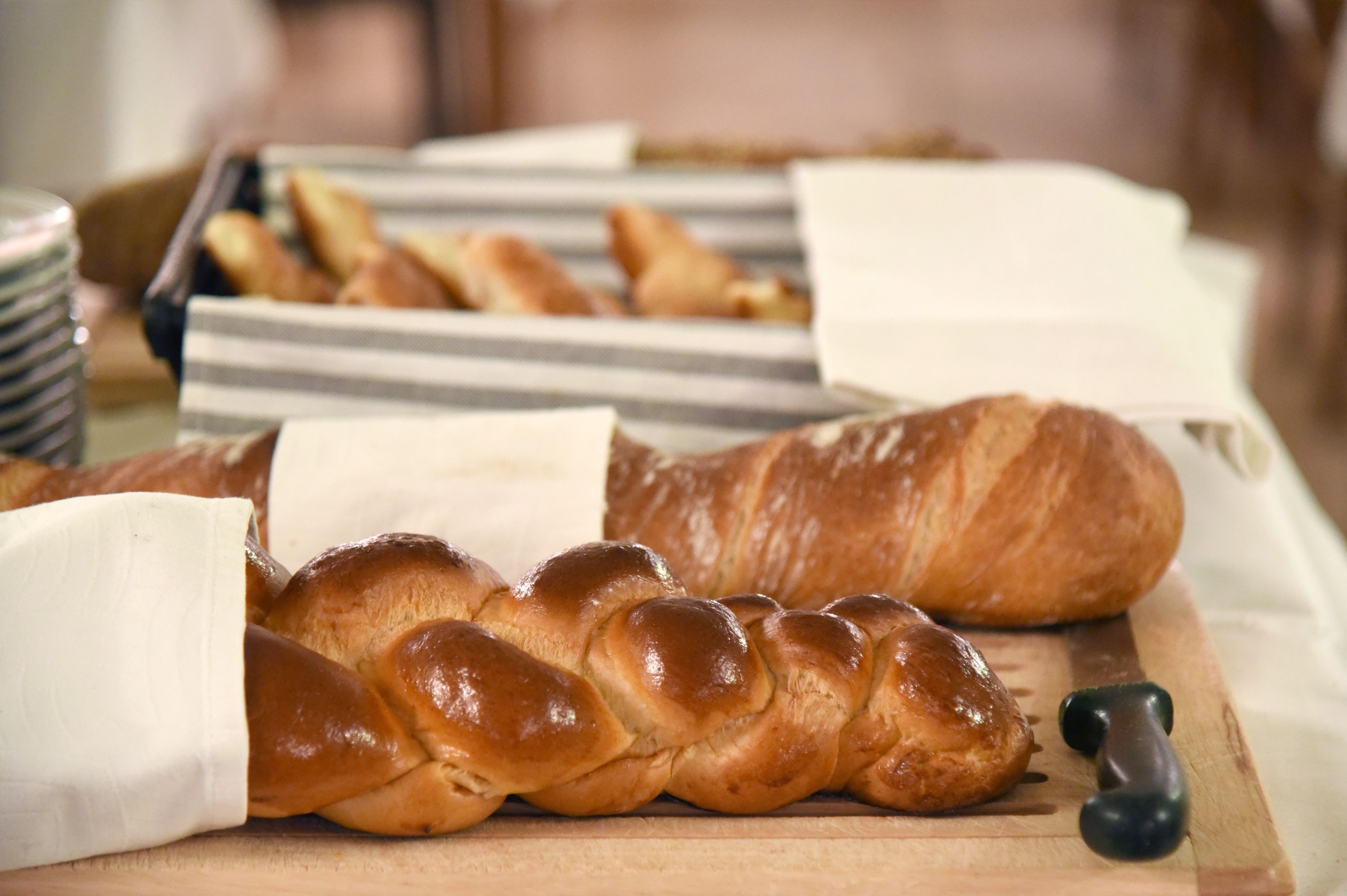 Una tabla de madera con una hogaza de pan trenzado y una hogaza de brioche.