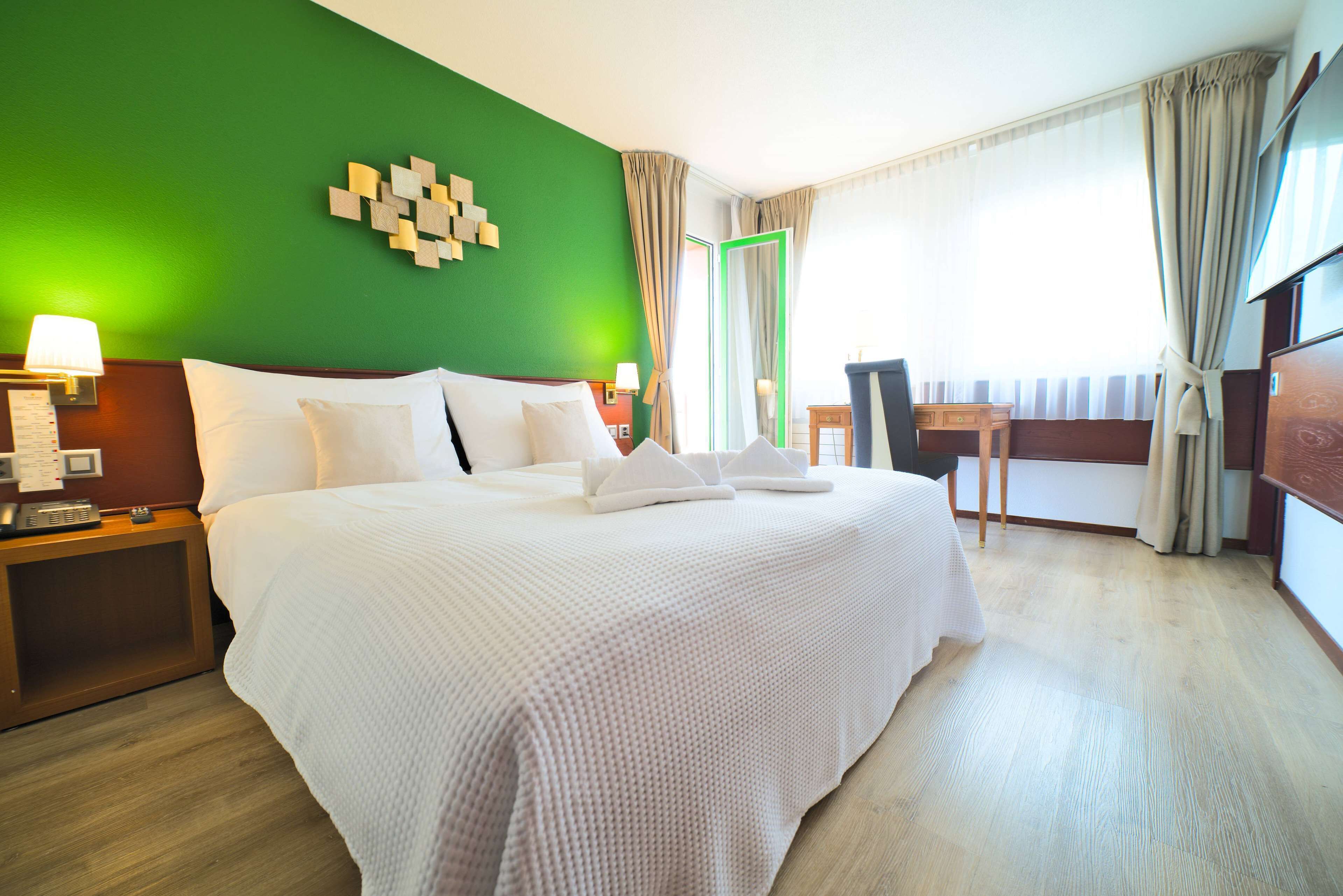 A hotel room with a large bed, a desk, and a chair.