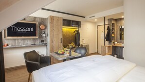 A hotel room with a bed, a desk with a chair, a coat rack, and a wardrobe. - Boutiquehotel Thessoni Classic Zürich (Regensdorf)