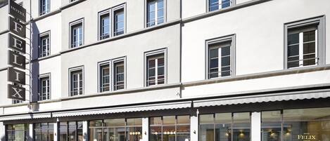 A hotel with a modern facade, large windows, and a visible restaurant area.