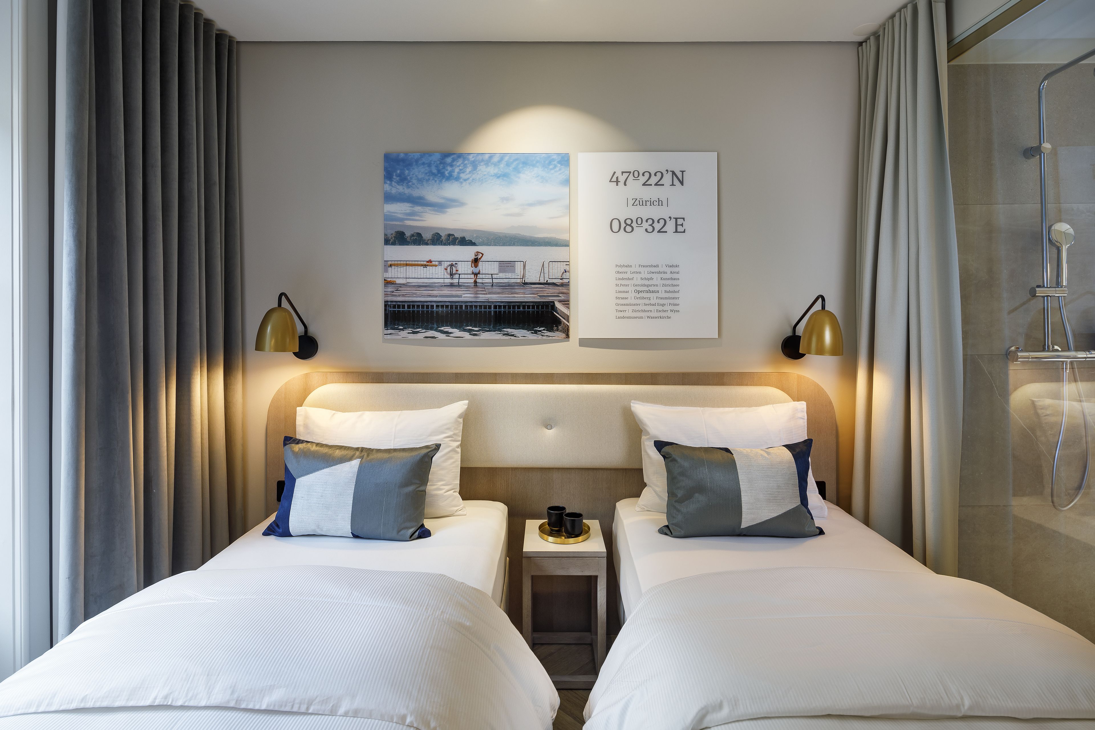 A hotel room with two beds, a nightstand, a framed picture, and a shower area.
