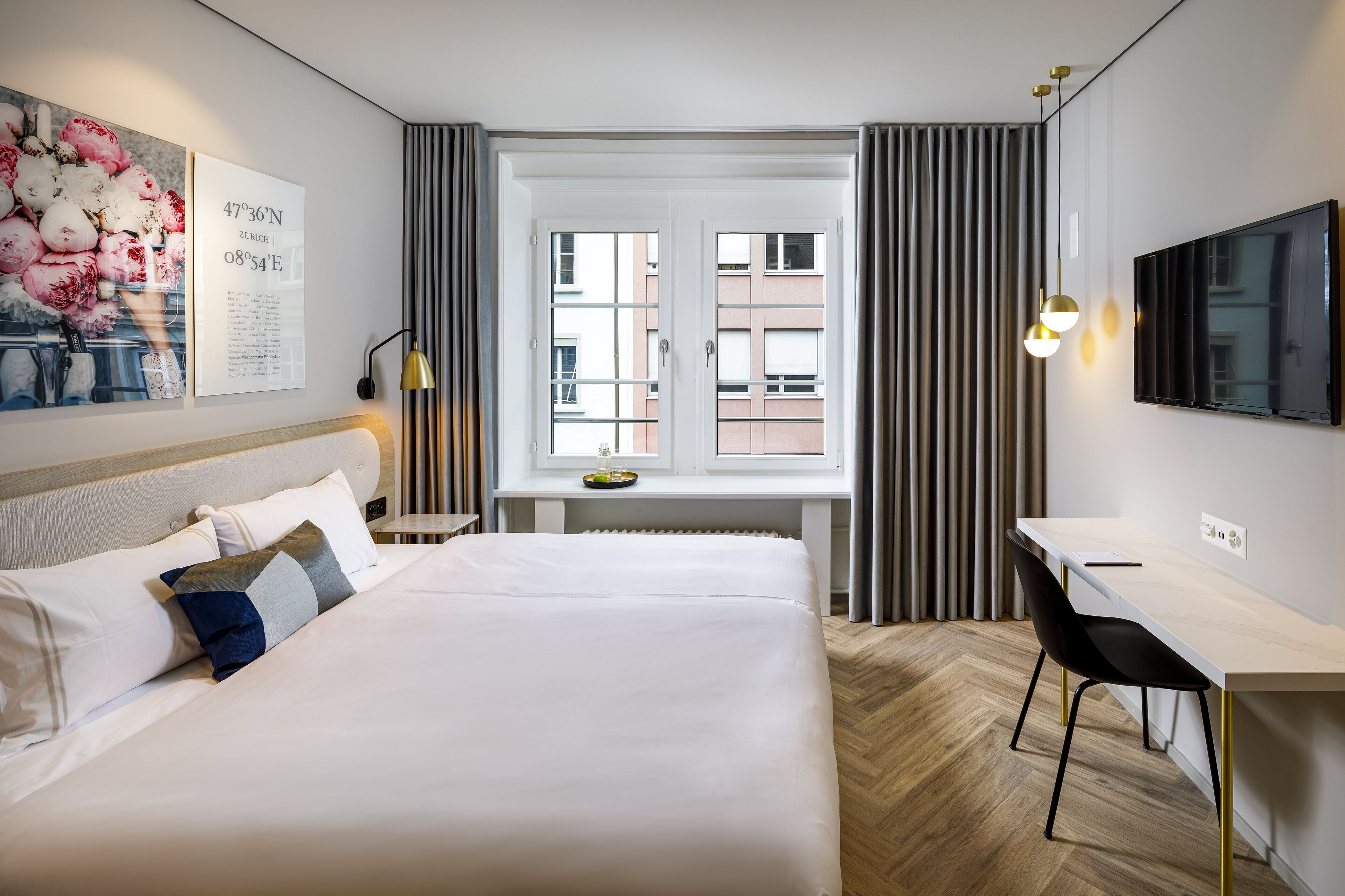 A hotel room with a large bed, a desk, a TV, and a window with curtains.