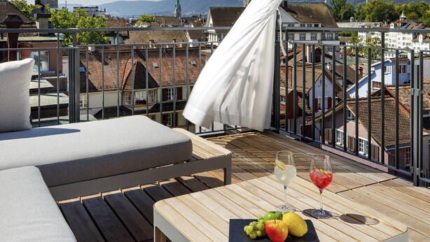 Une terrasse en bois avec un canapé et une table sur laquelle sont disposés des fruits et des boissons.