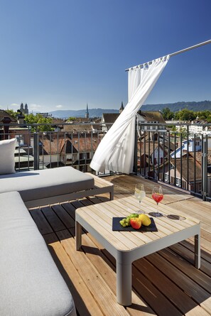 A wooden deck with a sofa and a table with fruit and drinks. - Hotel Felix (Zürich)