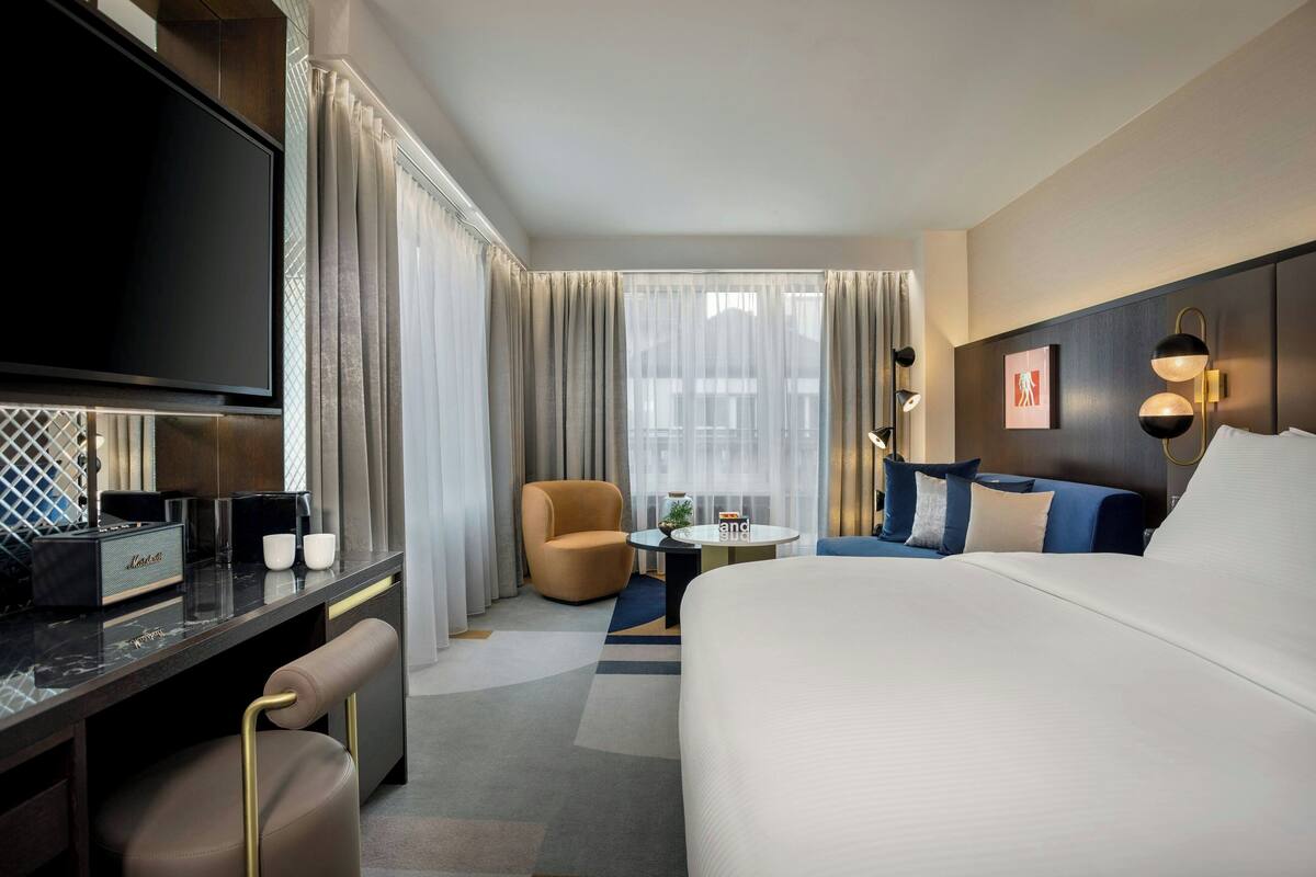 Une chambre d’hôtel avec un grand lit, un bureau doté d’un téléviseur à écran plat, une chaise, une petite table et un canapé.