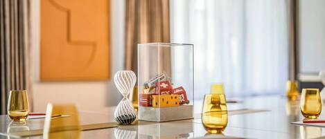 A hotel conference room with a glass table, golden glasses, and a decorative centerpiece with dice.