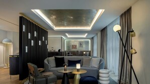 Een moderne woonkamer met een bank, salontafel, poef en een decoratieve scheidingswand.