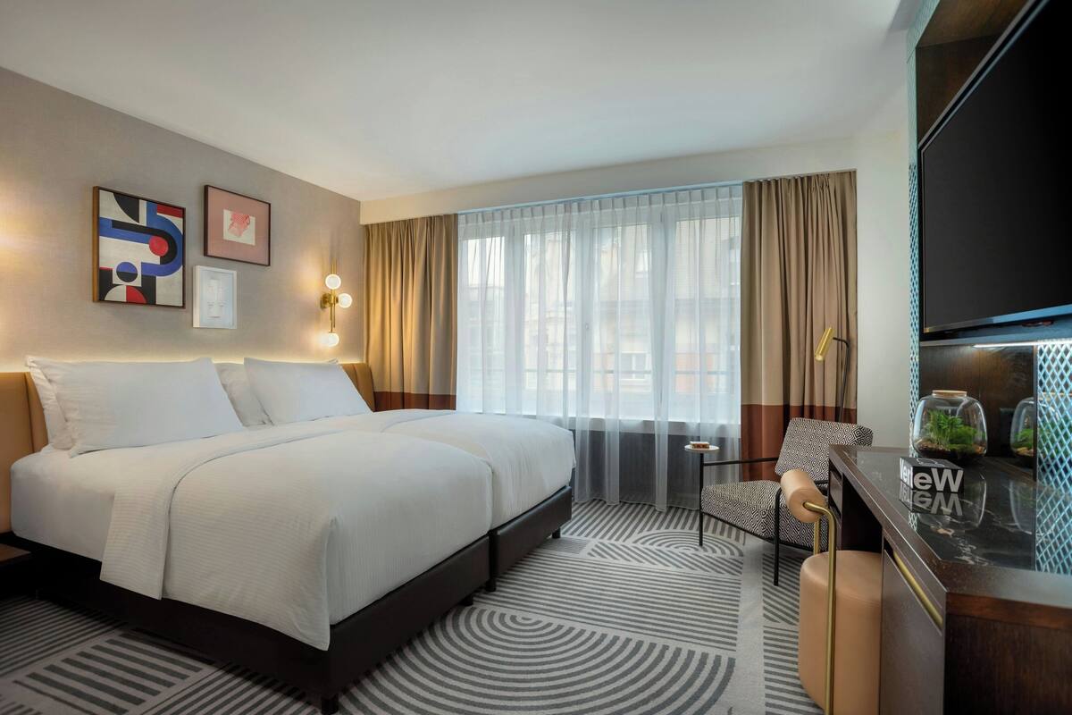 Une chambre d’hôtel avec un grand lit, un bureau avec un ordinateur, une chaise et un téléviseur.