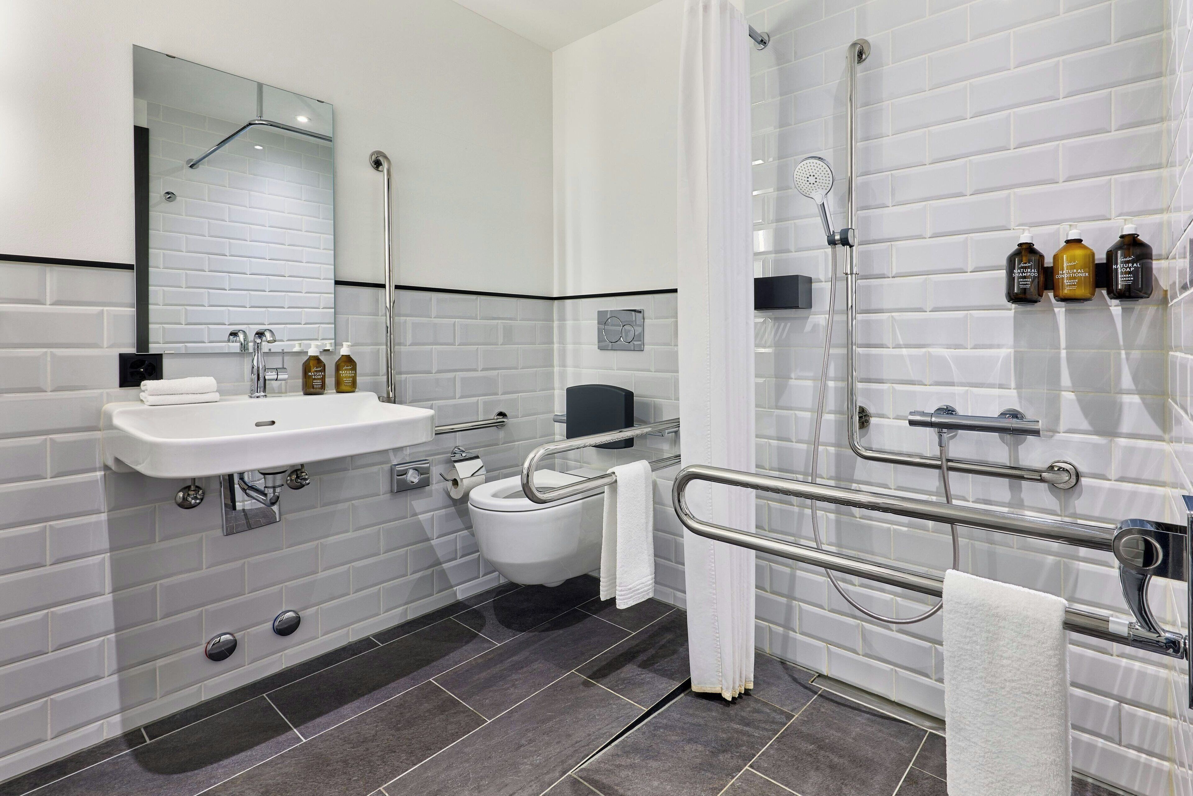Un baño moderno con lavamanos, inodoro y zona de ducha blancos.