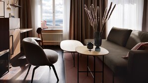 A modern living room with a sofa, armchair, and a small table with a vase of dried plants. - Sorell Boutique-Hotel Zürichberg (Zürich)