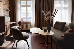 Una sala de estar moderna con un sofá, un sillón y una mesita con un jarrón de plantas secas.