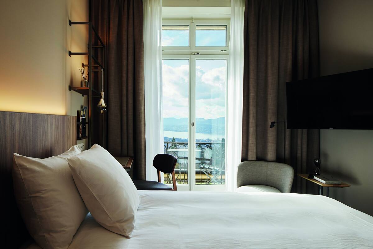 Une chambre d’hôtel avec un grand lit, une chaise, une télévision et un balcon avec vue.