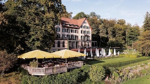 A large building with a garden patio area, outdoor seating, and a pool. - Sorell Boutique-Hotel Zürichberg (Zürich)