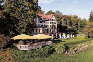 A large building with a garden patio area, outdoor seating, and a pool. - Sorell Boutique-Hotel Zürichberg (Zürich)
