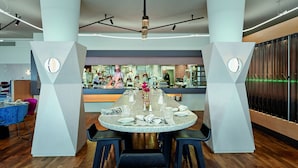 A modern dining area with a round table set for six, surrounded by black chairs. - Sorell Boutique-Hotel Zürichberg (Zürich)