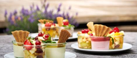 Tres copas de postre sobre una mesa de madera, con un fondo borroso de flores moradas.