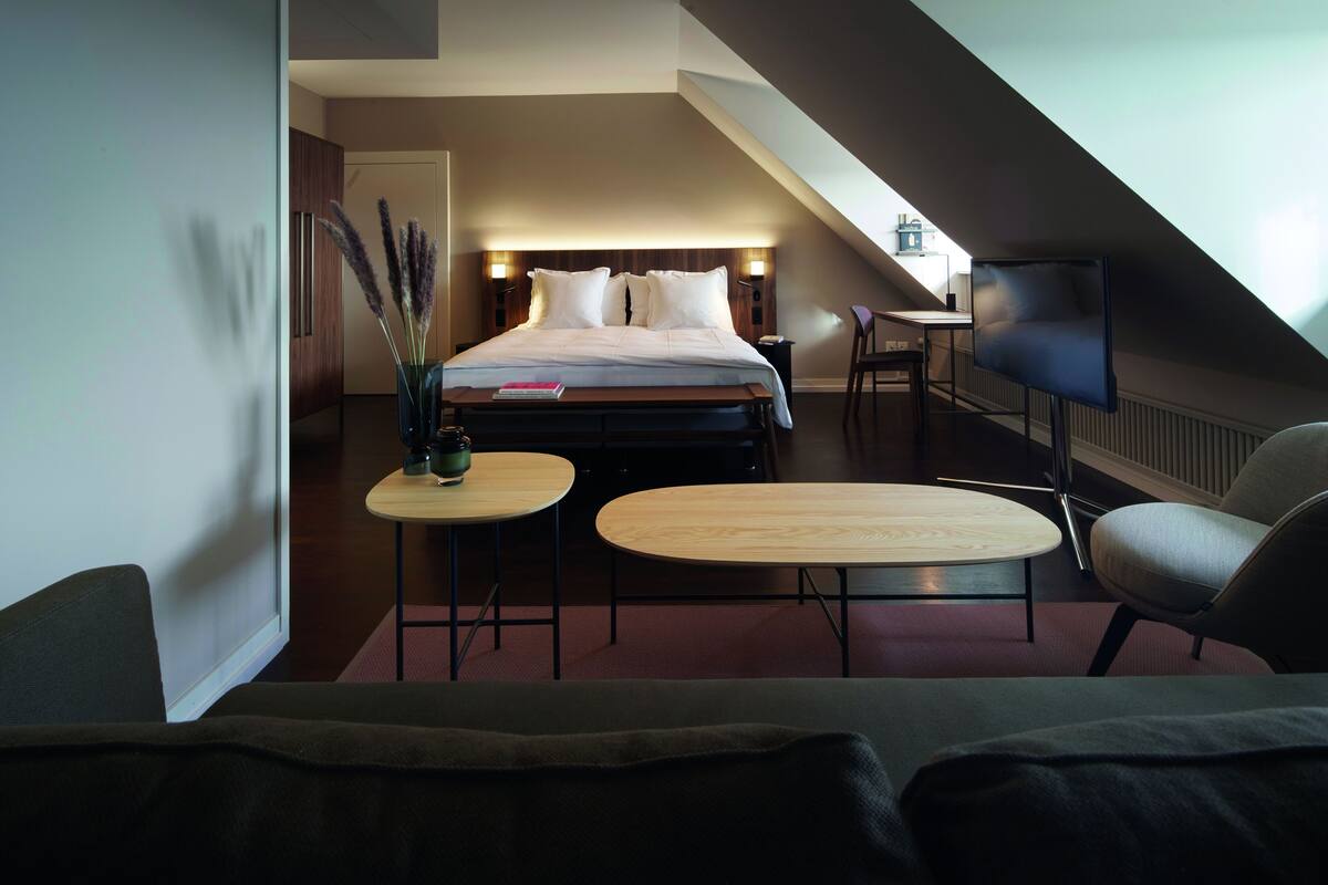 Une chambre d’hôtel moderne équipée d’un grand lit, d’une télévision, d’un bureau et de deux chaises.