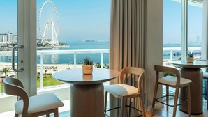 A balcony with a view of a Ferris wheel, beach, and water. There are two round tables and two chairs. - Sheraton Jumeirah Beach Resort (Dubai)