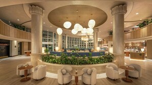 A spacious lobby with a central seating area, large columns, and a modern chandelier.