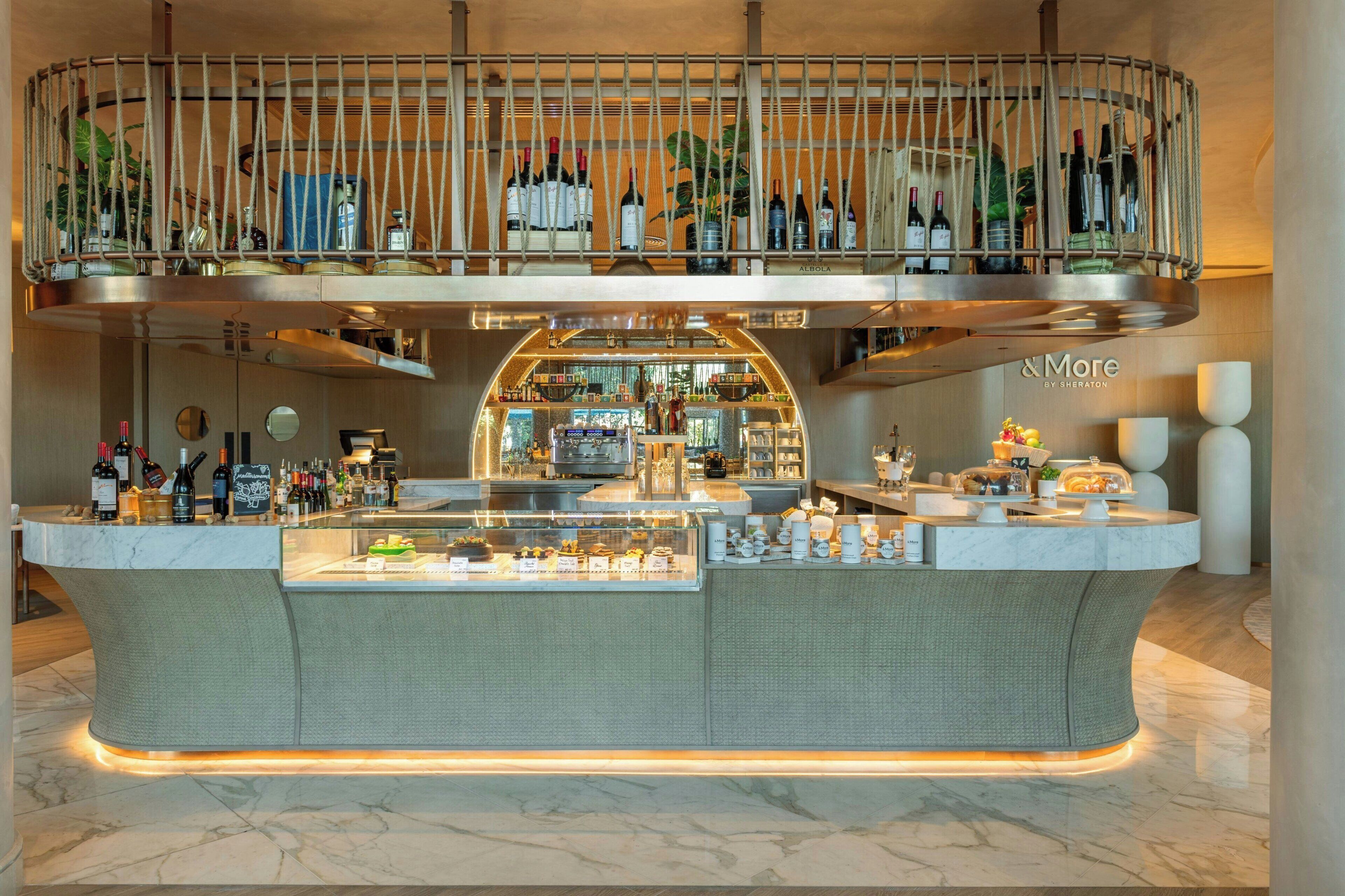 A bar area with a curved counter, a wine display above, and a sign reading "More by Sheraton".