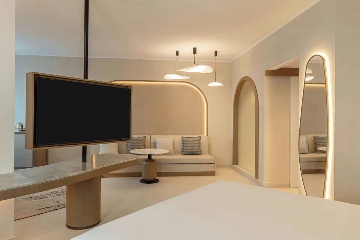 A modern living room with a flat-screen TV, a sofa, a coffee table, and pendant lights.
