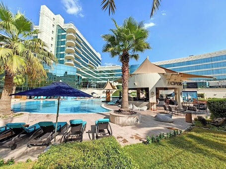 Outdoor pool, pool umbrellas, pool loungers. Millennium Airport Hotel Dubai