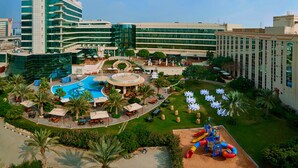 A hotel with a pool, outdoor seating, and a playground. - Millennium Airport Hotel Dubai (Dubai)
