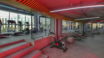Un gimnasio con cintas de correr, bicicletas estáticas y máquinas de pesas.