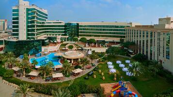 Relax by the pool surrounded by lush greenery and palm trees, with lounge chairs and umbrellas at your disposal.