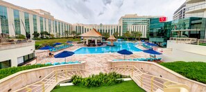 Uma área de piscina de hotel com um gazebo, espreguiçadeiras e um gramado bem cuidado.