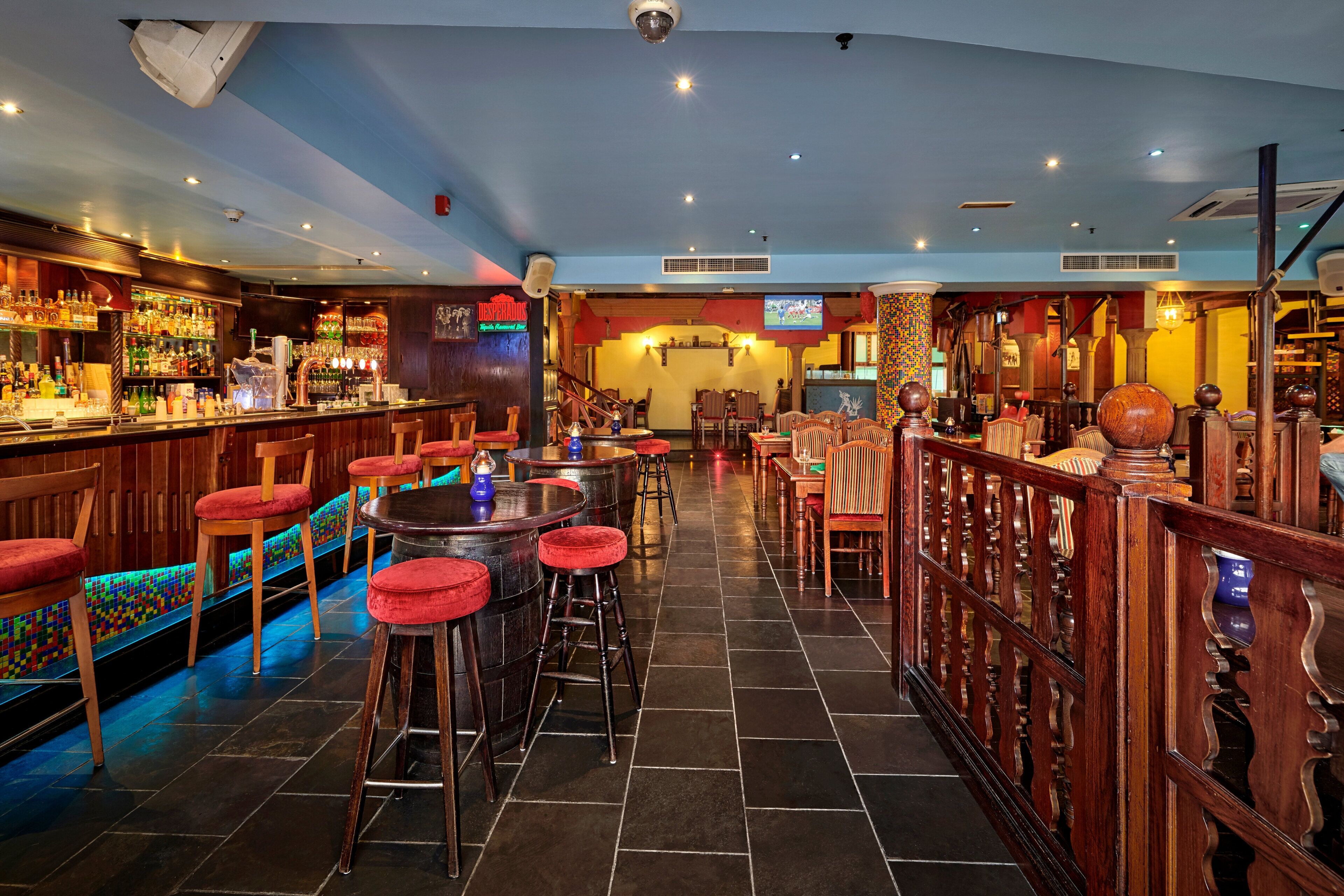 A bar area with stools, tables, and a bar counter.