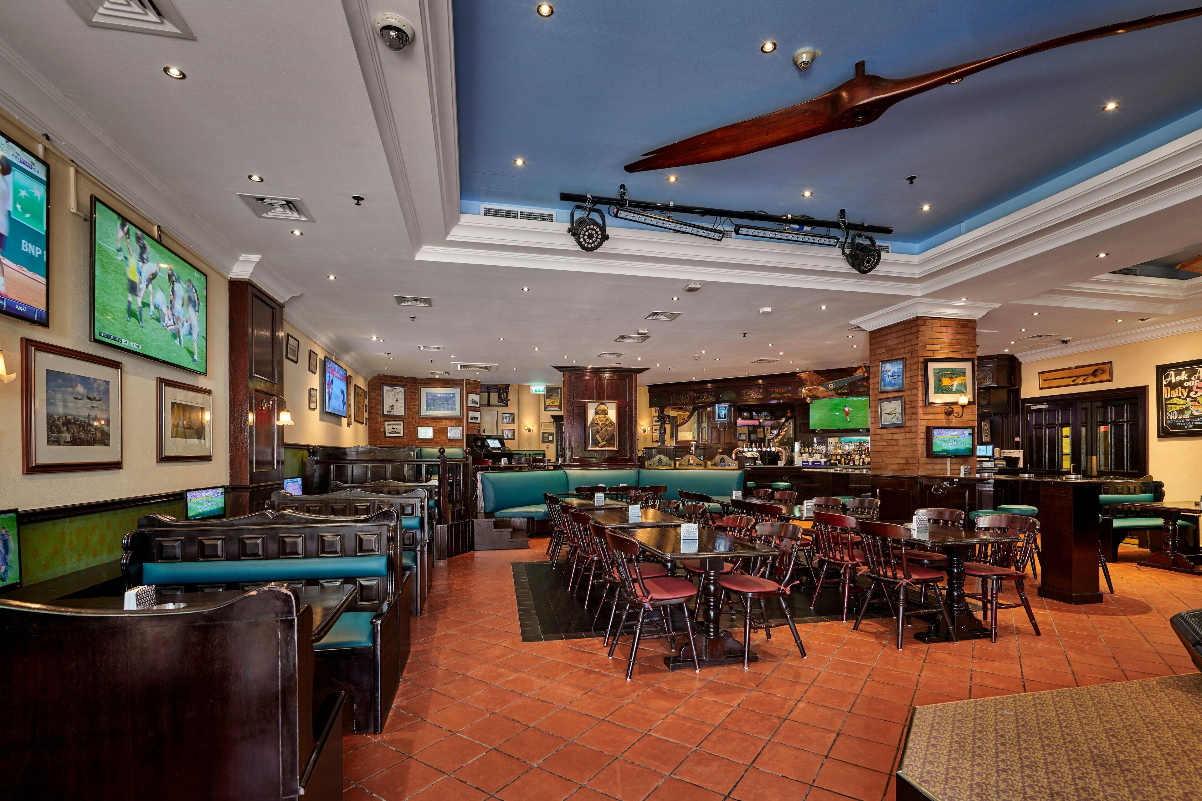A restaurant with booths, tables, and chairs, featuring a blue ceiling and tiled floor.