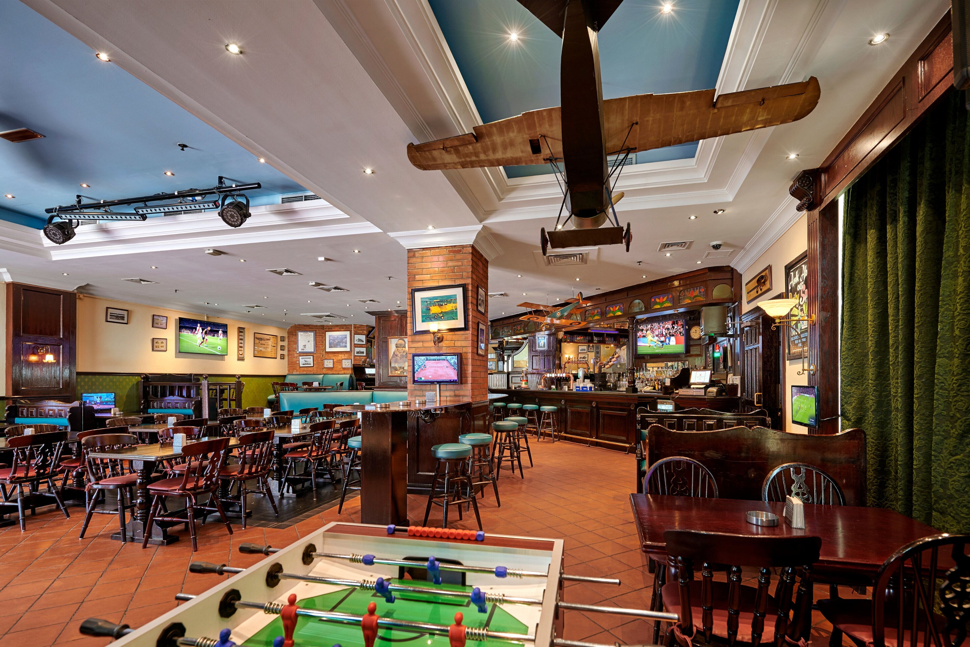 Eine Bar mit einer Fußballtischkickeranlage, Sitzgelegenheiten und einer Bar.