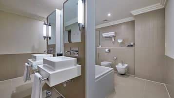 Un baño moderno con dos lavabos, un espejo grande, una bañera y un inodoro.