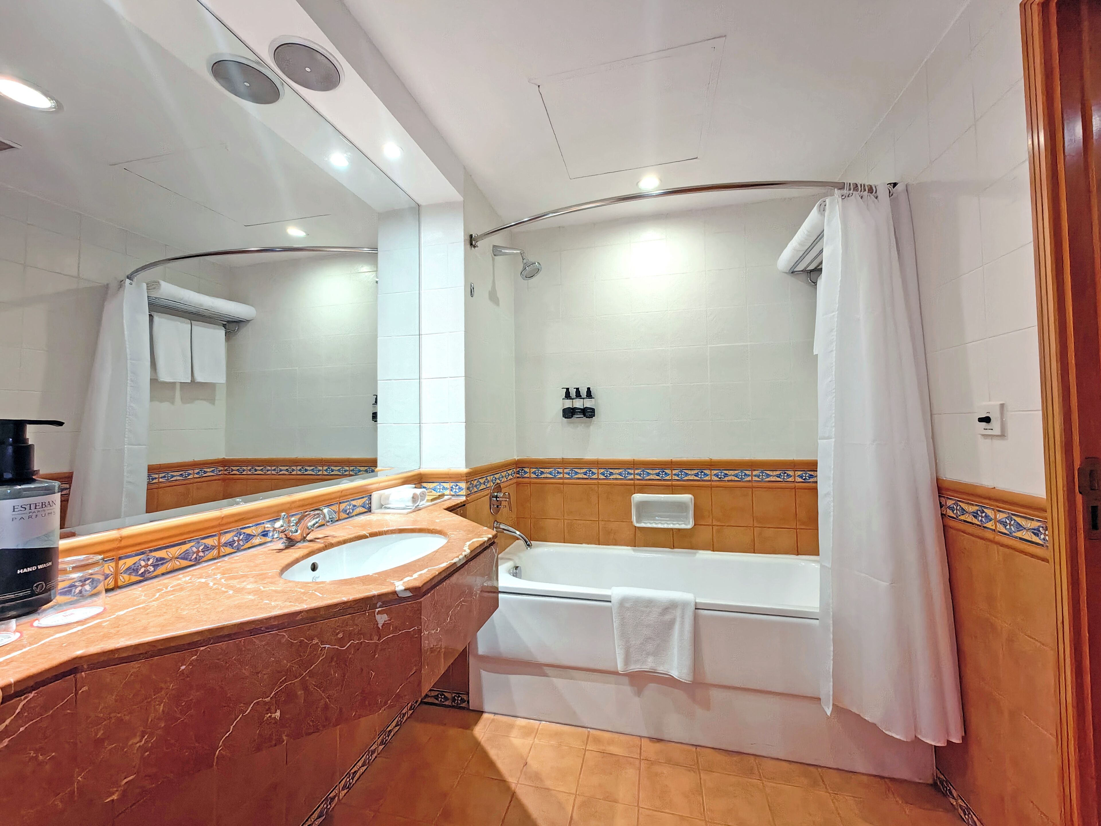 A bathroom with a marble sink, a bathtub, and a shower curtain.