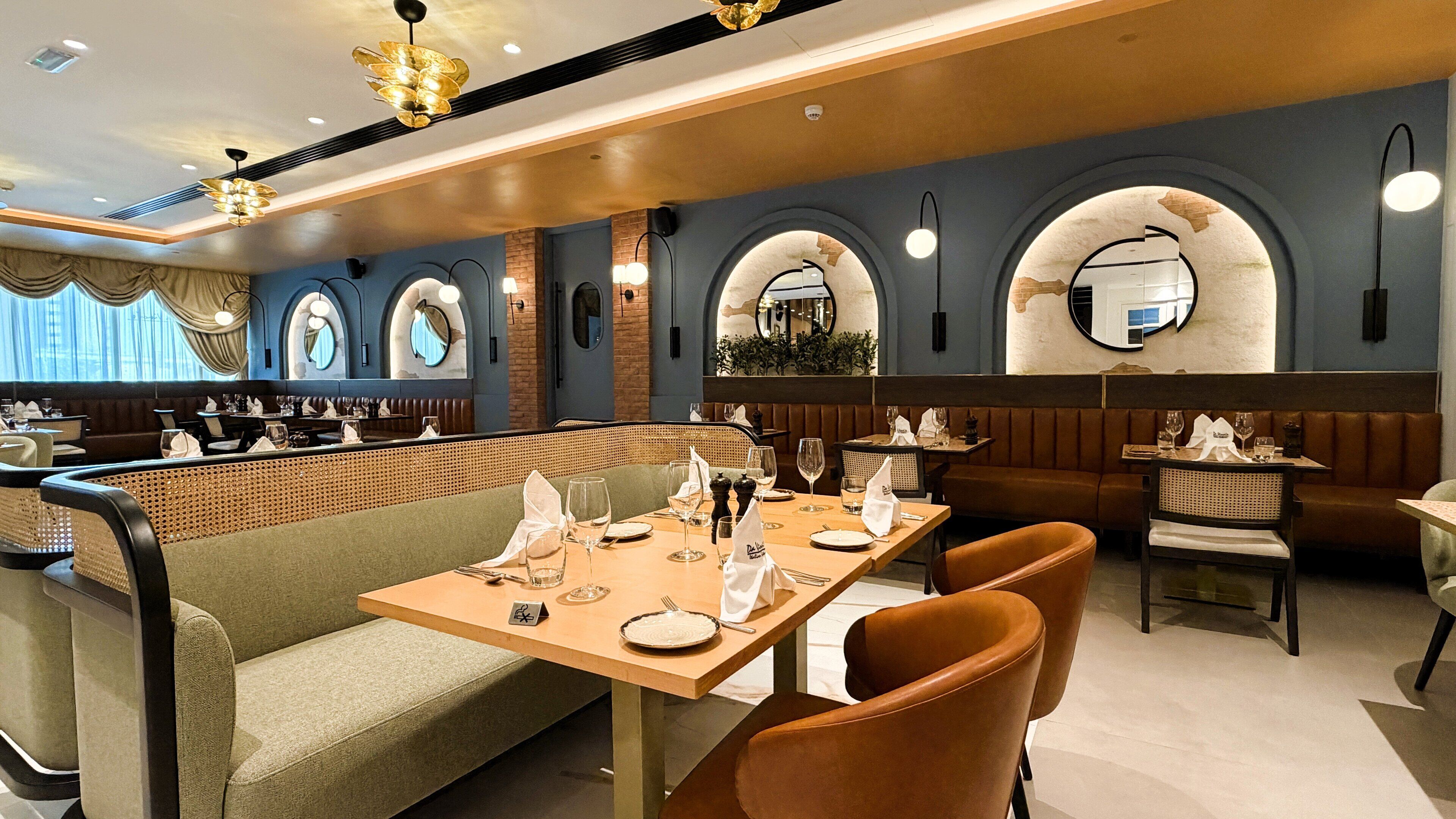 A restaurant with booths and tables, some with white napkins and cutlery.
