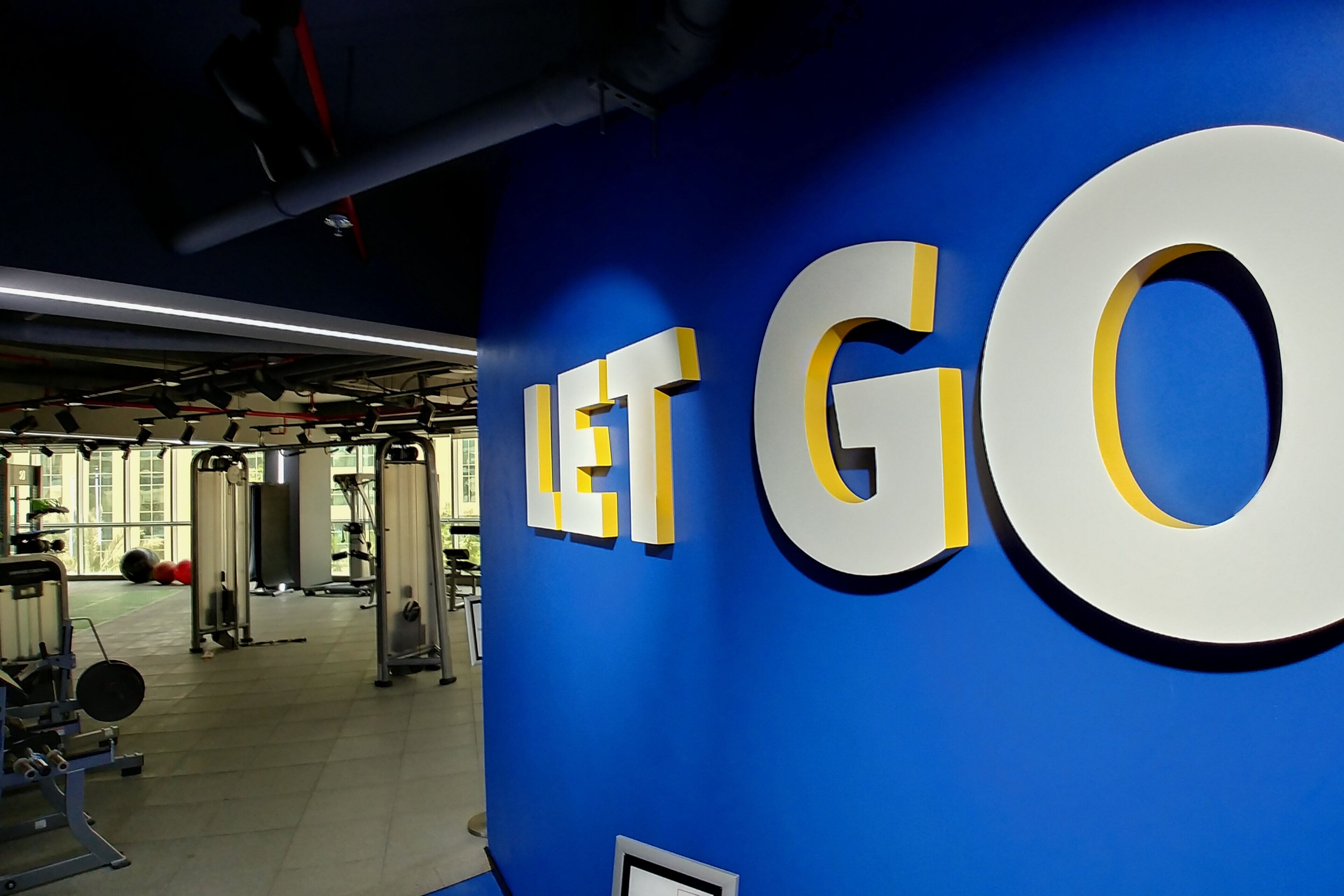 Une salle de sport avec un mur bleu et les mots « LET GO » écrits en grandes lettres.