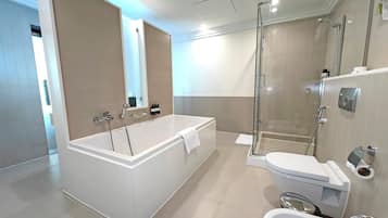 A modern bathroom with a large bathtub, a separate shower area, and a toilet.