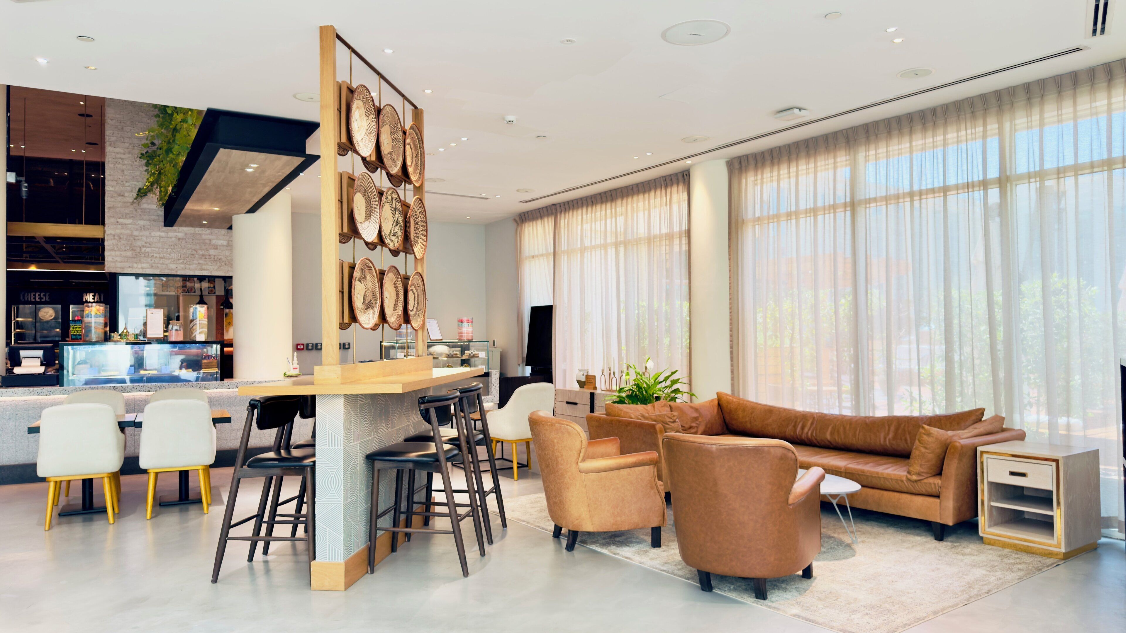 A modern living area with a sofa, chairs, a coffee table, and a bar area with stools.
