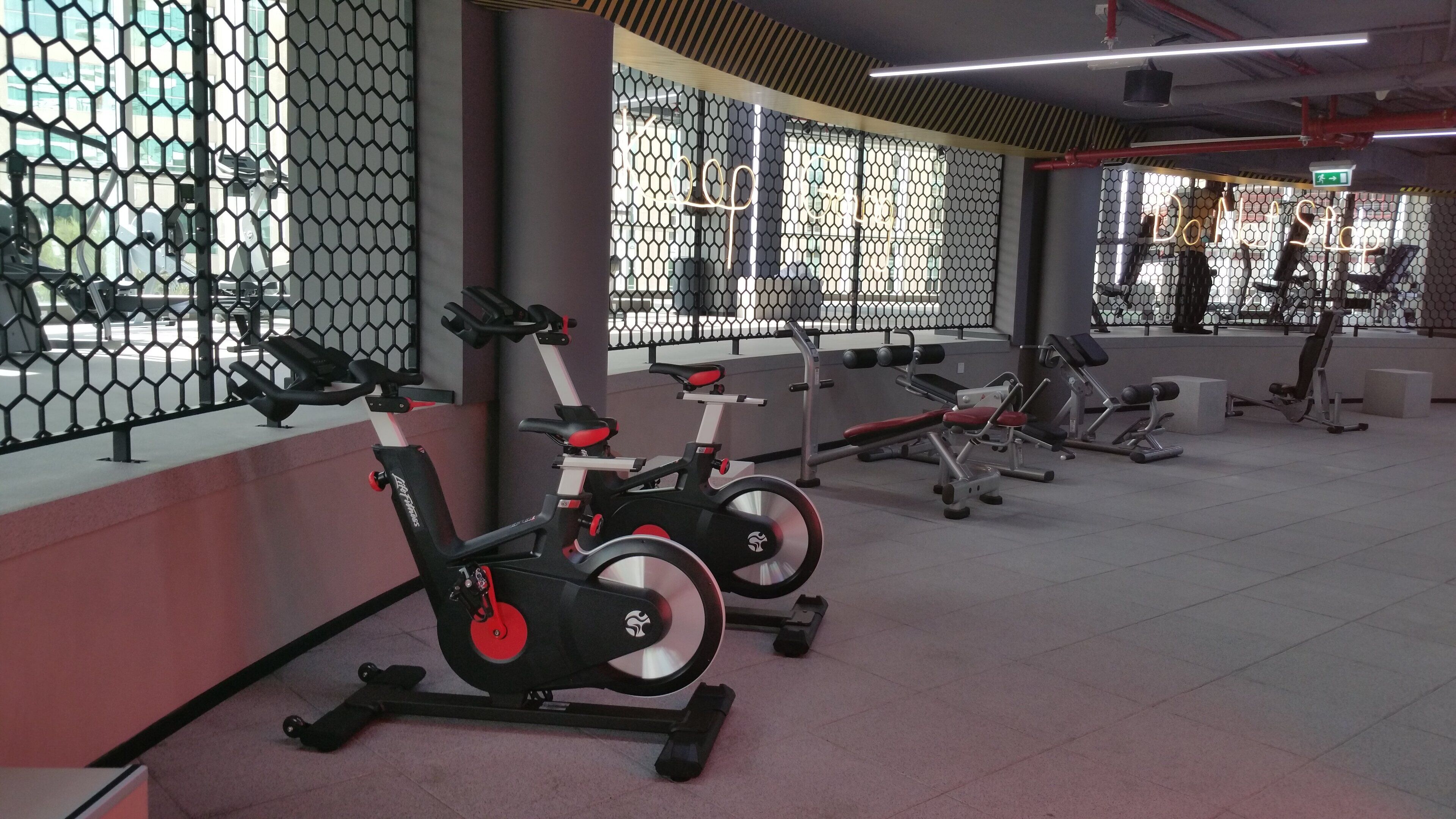 A gym with stationary bikes, weight machines, and a mirrored wall.