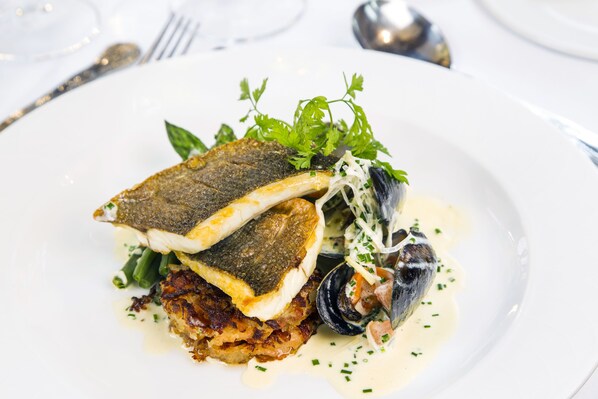 A seafood dish on a white plate with a fork and spoon in the background. - Classic Lodges - The White Swan (Alnwick)