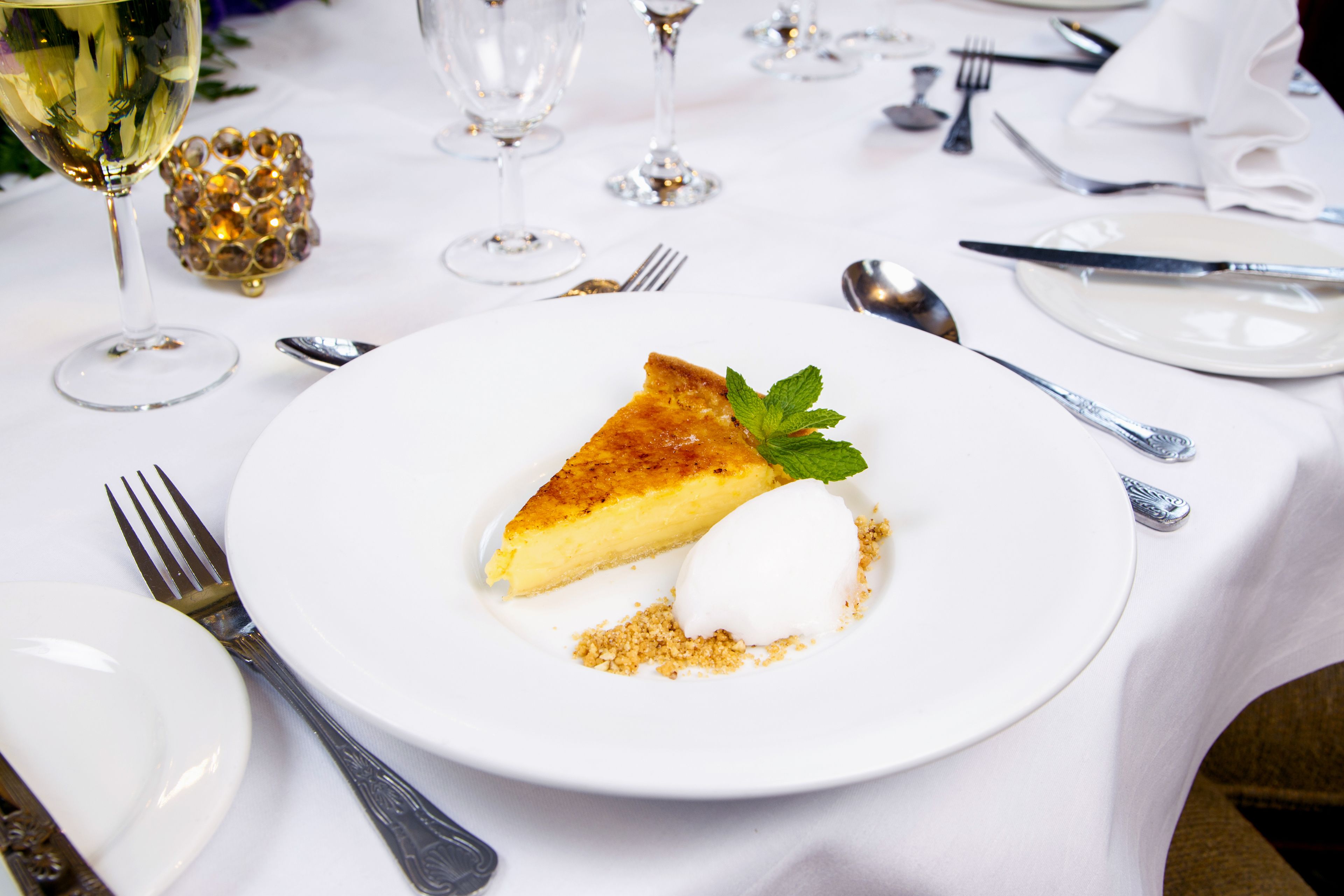 A dessert plate with a slice of pie and a scoop of ice cream, accompanied by a mint leaf garnish.