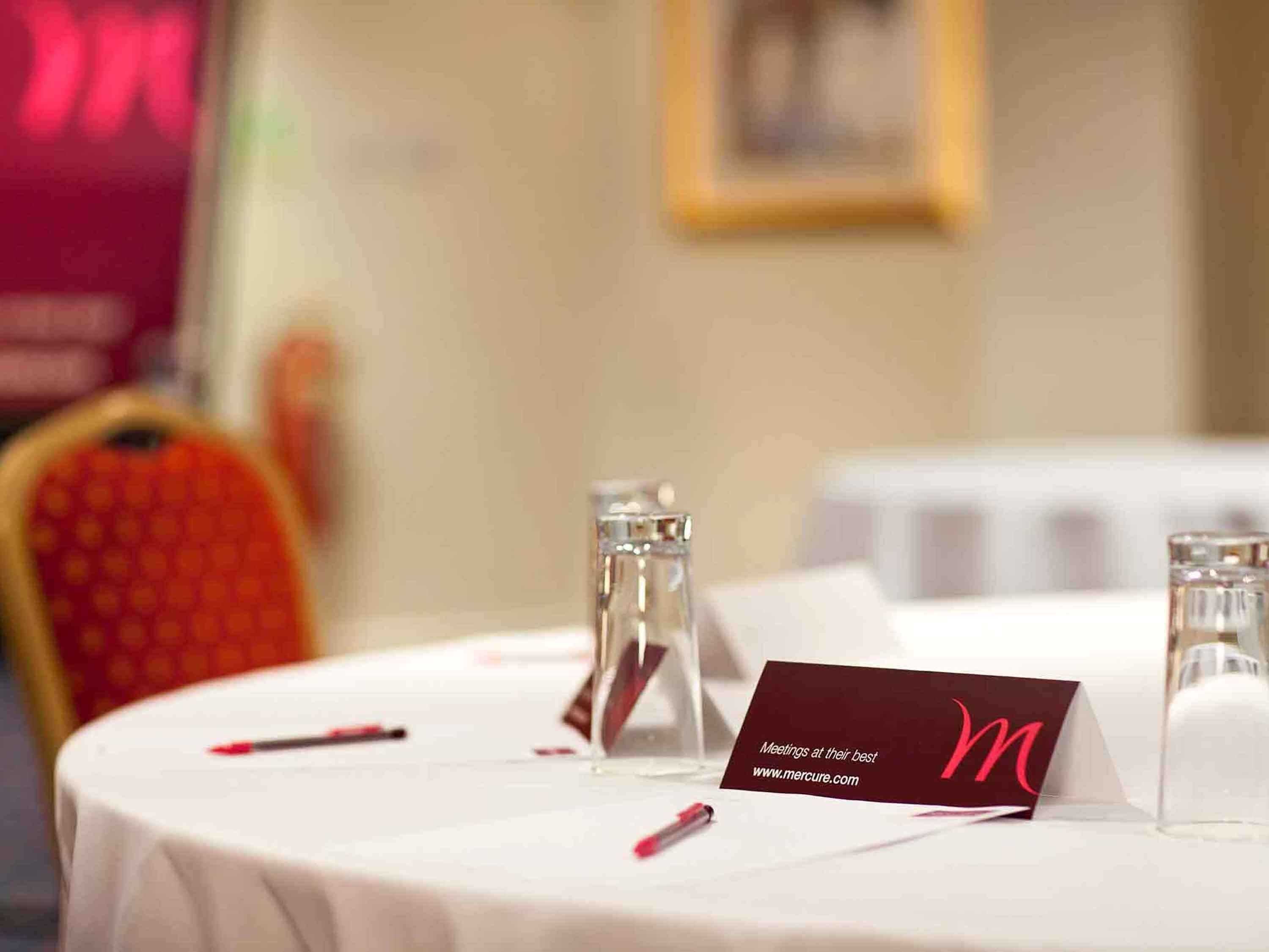 A conference table with a name card, two glass bottles, and a red pen.