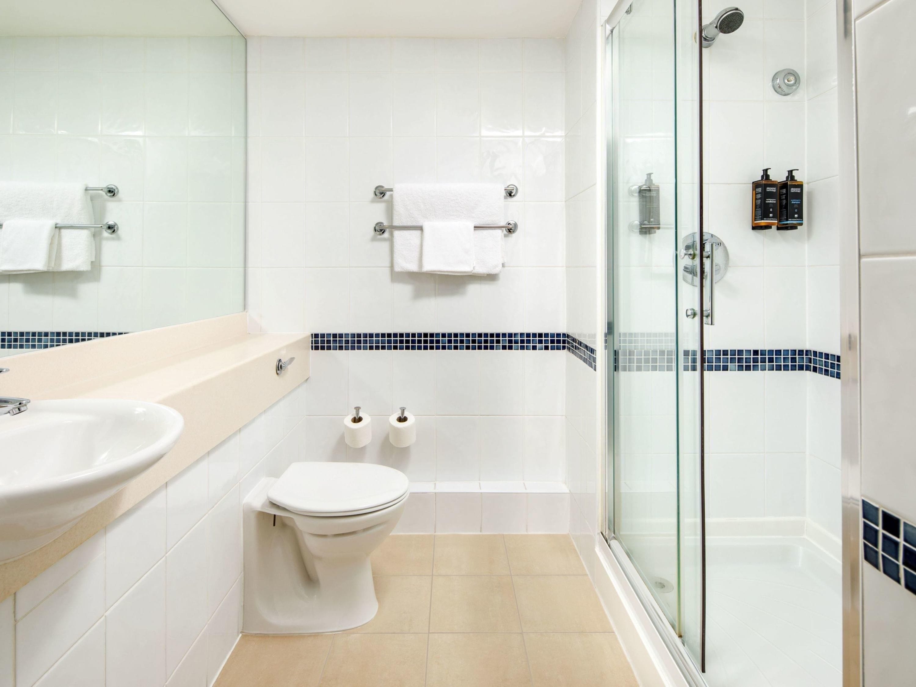 Un baño moderno con cabina de ducha de vidrio, un lavabo, un inodoro y un espejo.