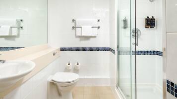 Un baño moderno con cabina de ducha de vidrio, un lavabo, un inodoro y un espejo.