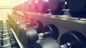 Eine Reihe von Kurzhanteln an einem Gewichtsständer in einem Fitnessstudio.