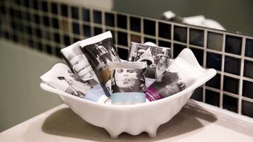 A white basin filled with various magazines and a tissue box on a countertop.