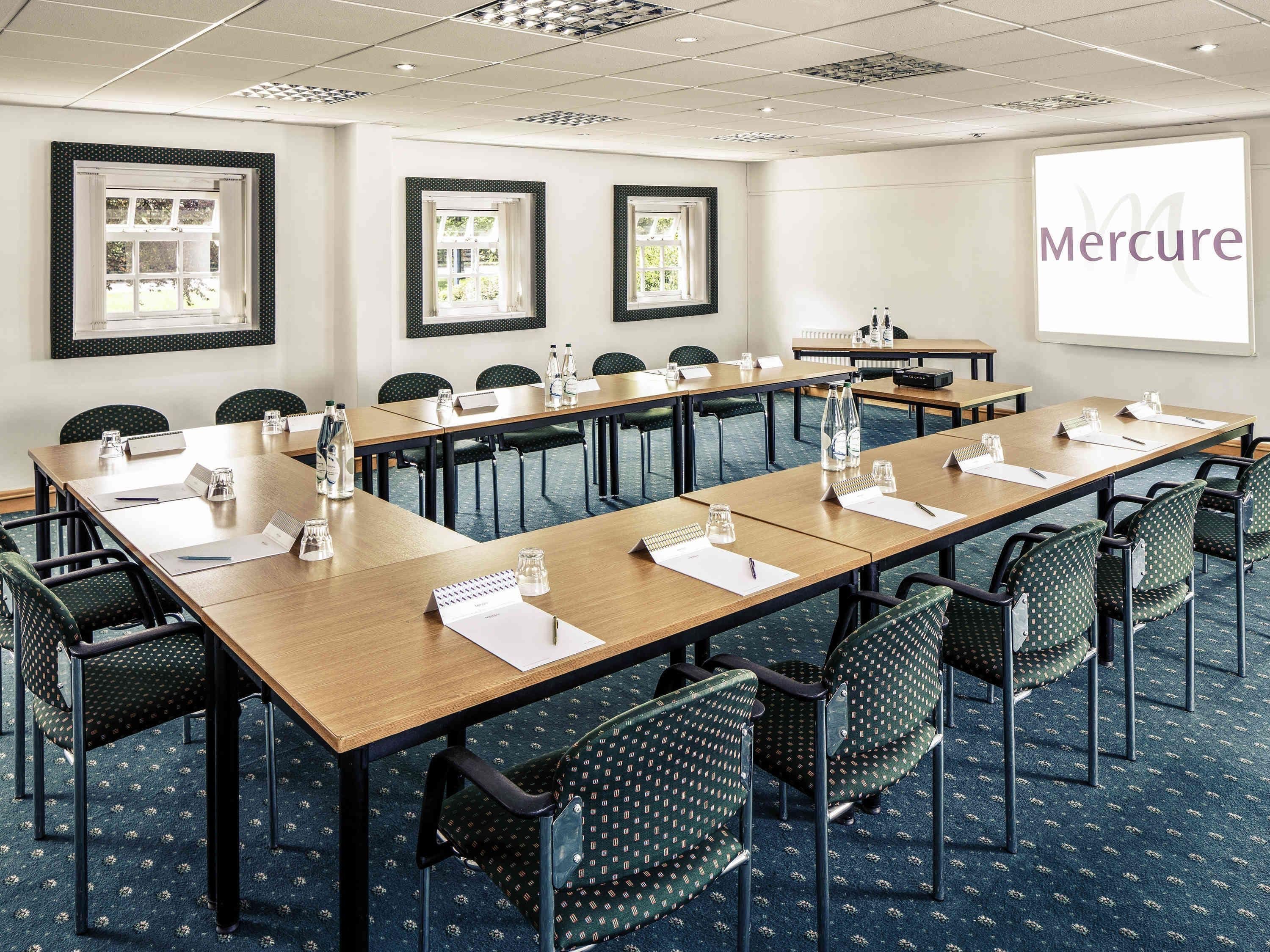 Une salle de conférence avec une longue table, des chaises et un écran de présentation sur lequel figure le mot « Mercure ».