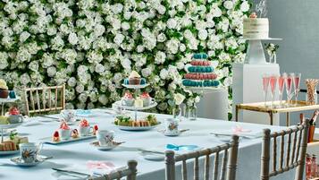 A table set for a tea party with floral decorations and a cake on a stand.
