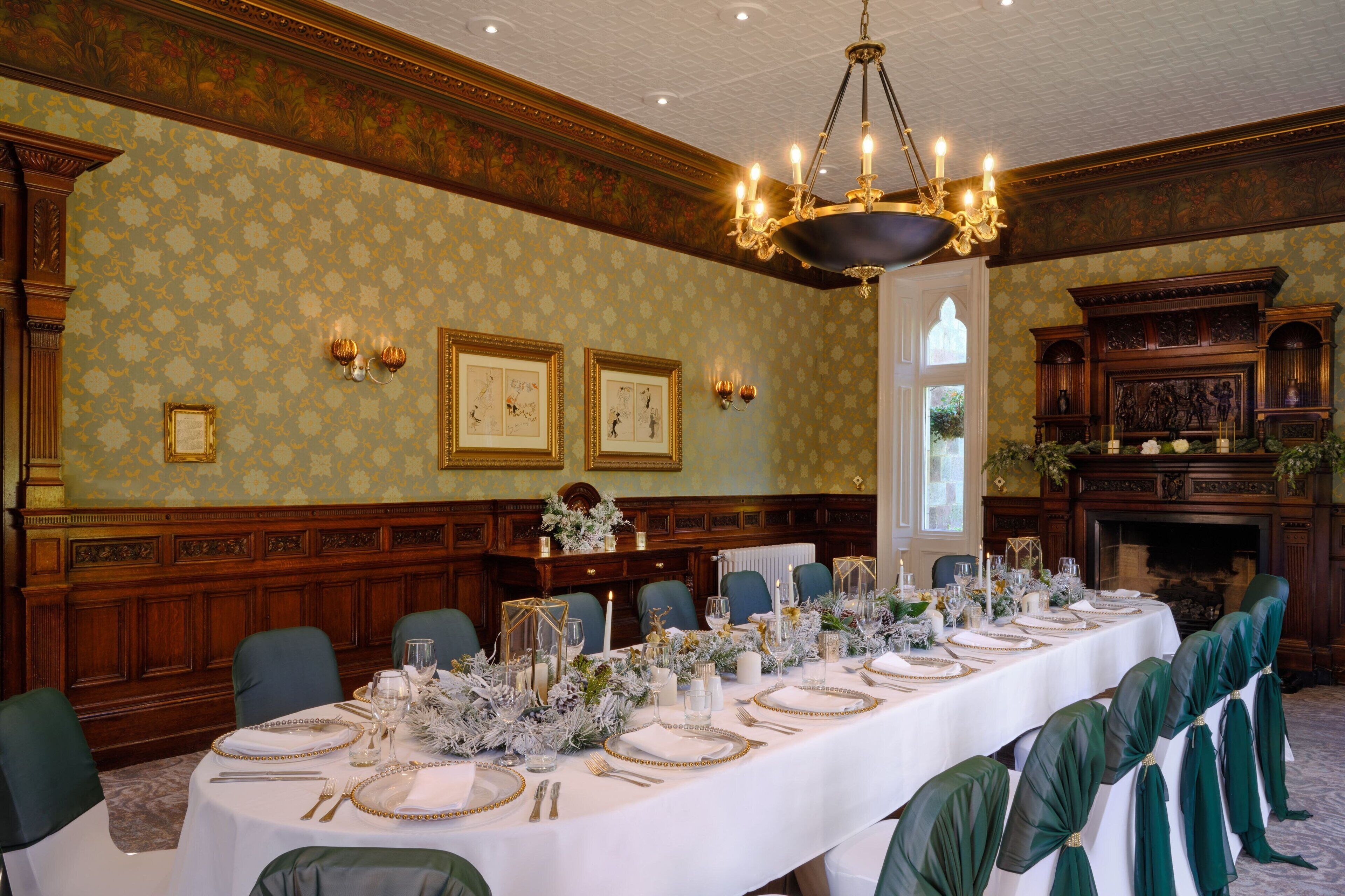 Un comedor formal con una larga mesa dispuesta para un banquete, paneles de madera y una araña.